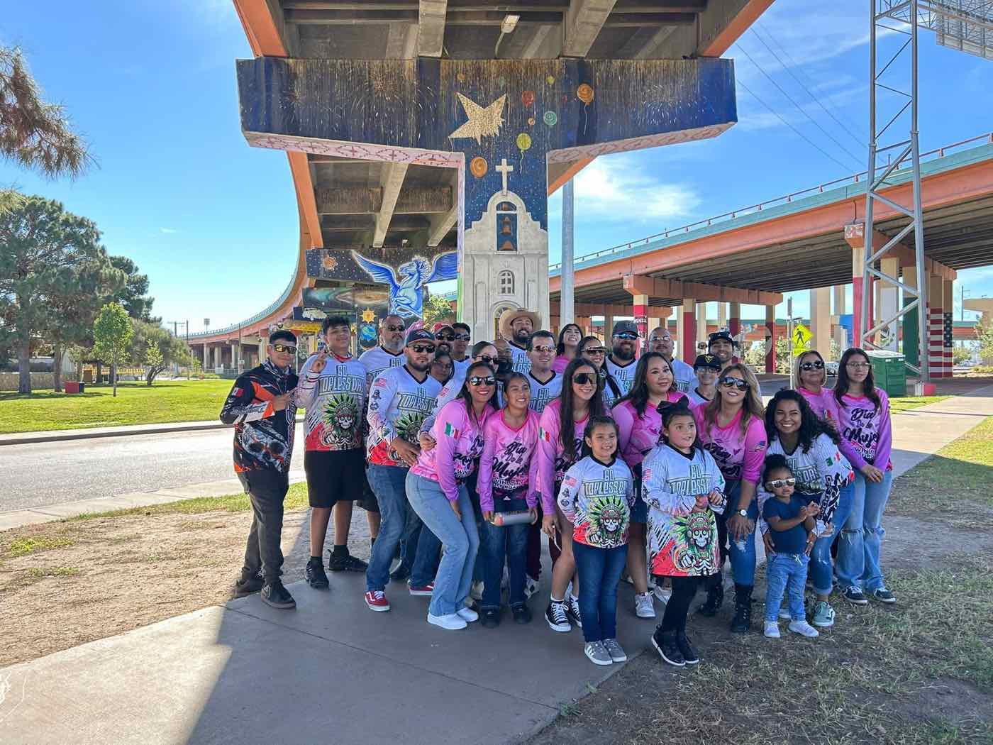 Members of Twin City Offroad in matching shirts gathered beneath colorful freeway murals